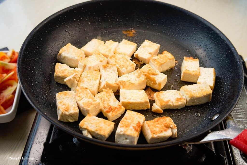 Tofu cubes being fried in the black pan