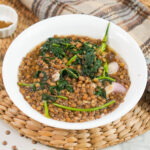 a bowl of Filipino lentil soup being served at the table