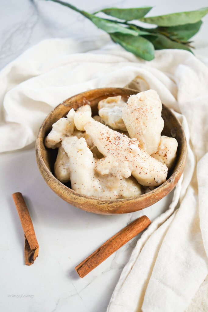 freshly cooked taro with coconut milk served in a wooden bowl with cinnamon sticks on the table