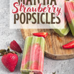 matcha strawberry popsicles placed on a wooden board with fresh strawberries