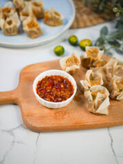 Vegan Siomai on a wooden board with a chili garlic oil sauce in a small white bowl