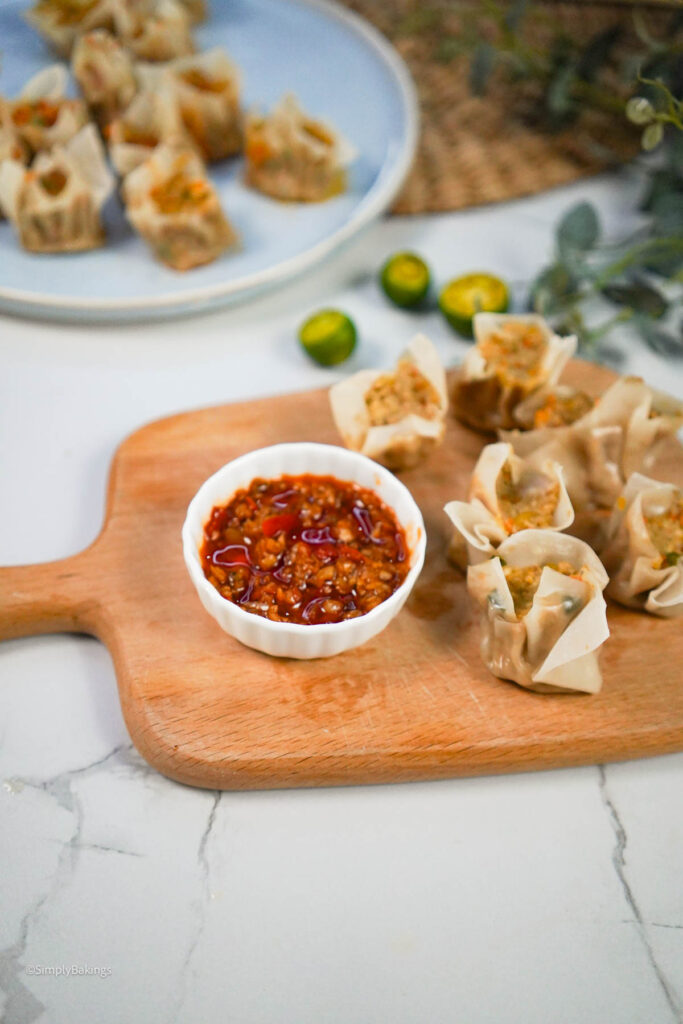 Vegan Siomai on a wooden board with sauce in a small white bowl
